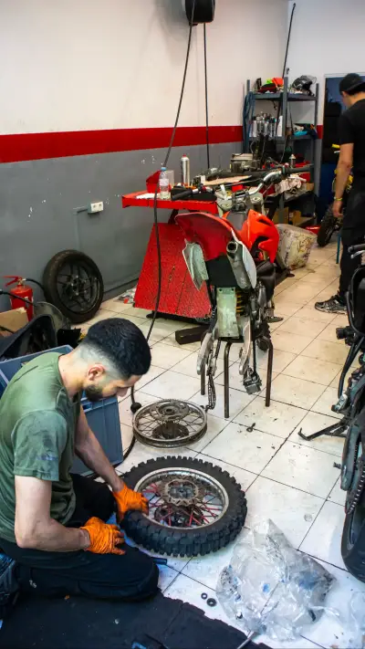 Un mécanicien ganté travaille sur une roue déposée dans l’atelier.